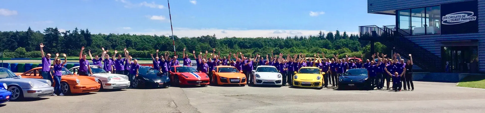 Un groupe d'entreprise réuni devant une flotte de voitures de sport chez CIRCUITS PARIS OUEST